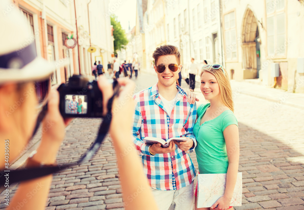 smiling couple with map and photo camera in city