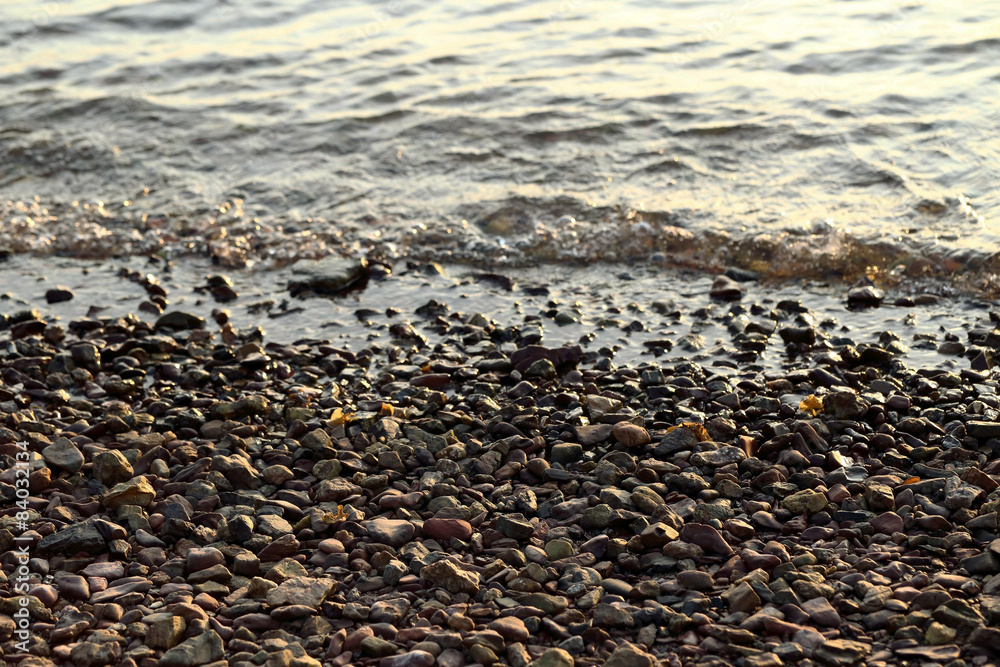 Sea pebble - gravel beach in sunlight, selective focus for backg Sea pebble - gravel beach in sunlight, selective focus for backg