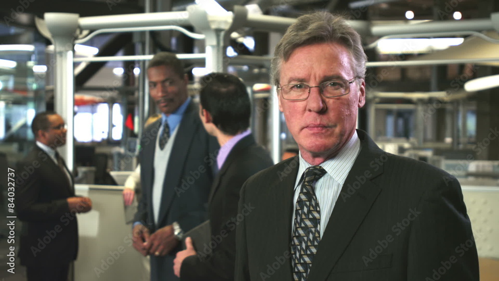 An older businessman sits at a table and takes part in a meeting