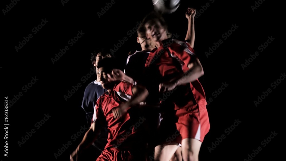 A group of soccer players jump up and try to head a ball A group of soccer players jump up and try to head a ball