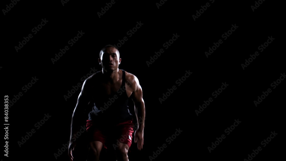 An athlete jumps up and down to get warmed up and ready in a dark room An athlete jumps up and down to get warmed up and ready in a dark room