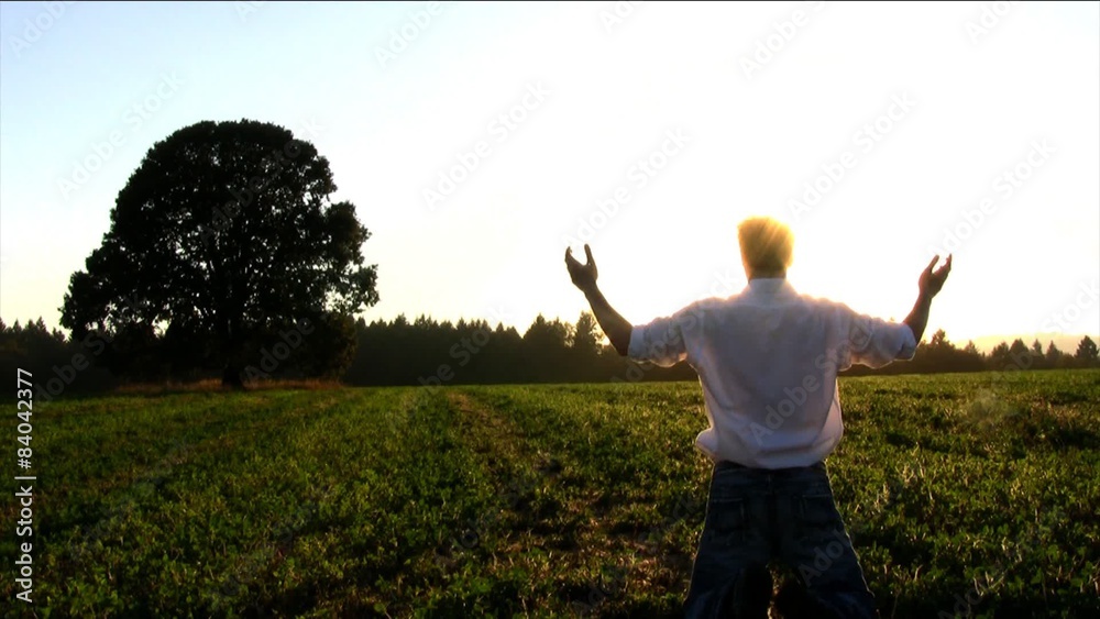 Man Kneeling and Raising his Hands at Sunset Man Kneeling and Raising his Hands at Sunset