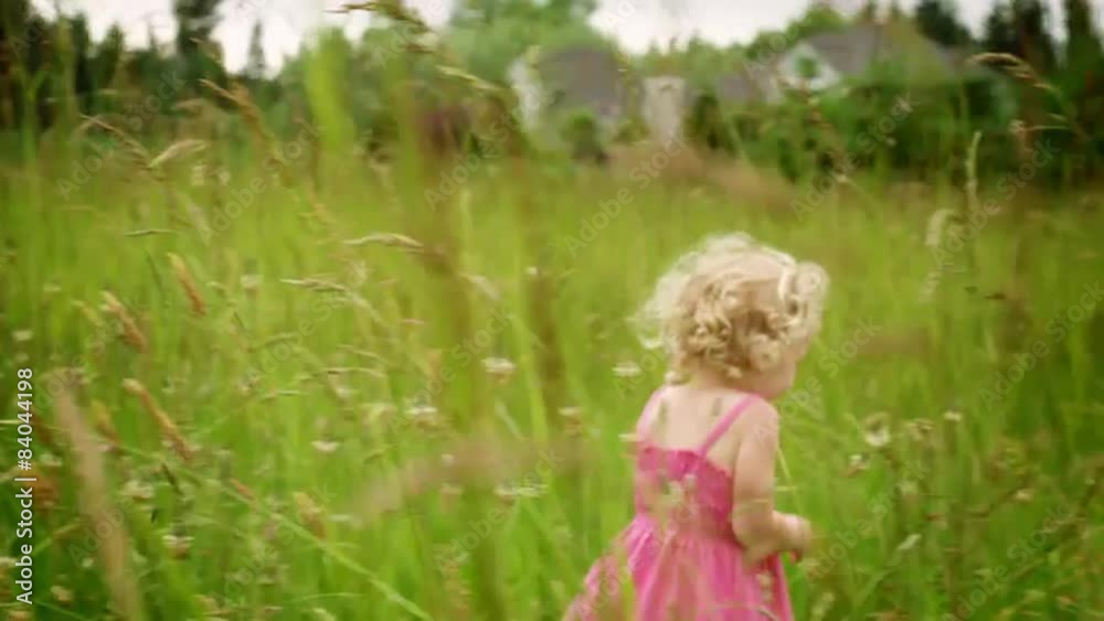 A young blonde girl runs in a green field during the day A young blonde girl runs in a green field during the day
