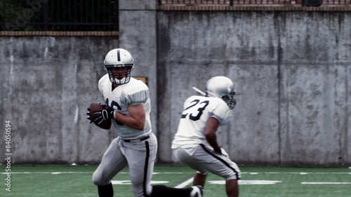 A Quarterback hikes the ball from the line of scrimmage and throws a pass.