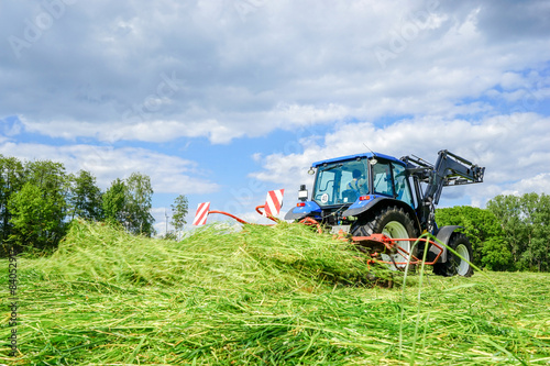 Heuernte, Traktor mit Heumaschine beim Gras wenden photo