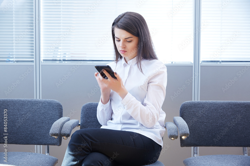 Obraz premium business woman with mobile phone sits in the office