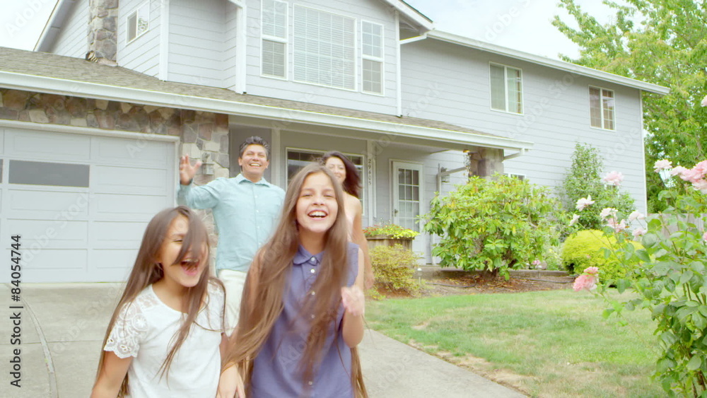 A family runs out of their house towards the camera and then stops and smiles