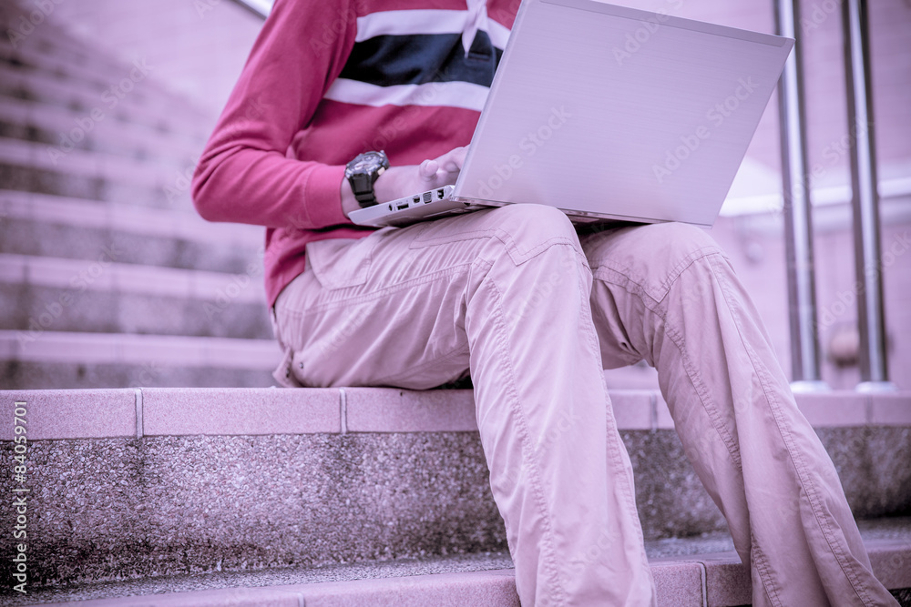 Young man using laptop on the steps