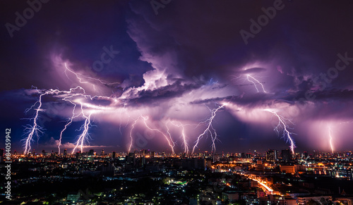 Fotografie, Obraz Lightning storm over city in purple light