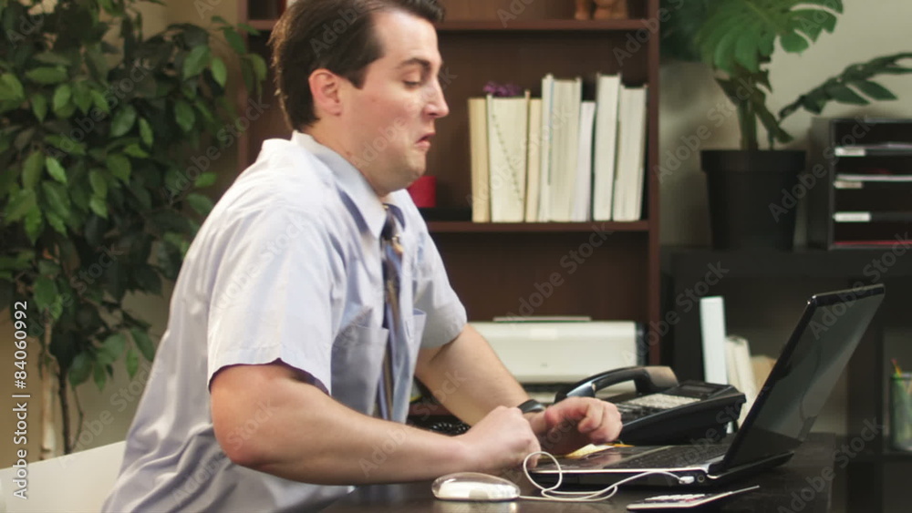 An angry businessman punches and then head-buts his computer. Slow motion