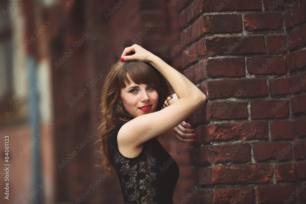 Fototapeta premium beautiful sexy brunette woman standing near a brick wall in dres