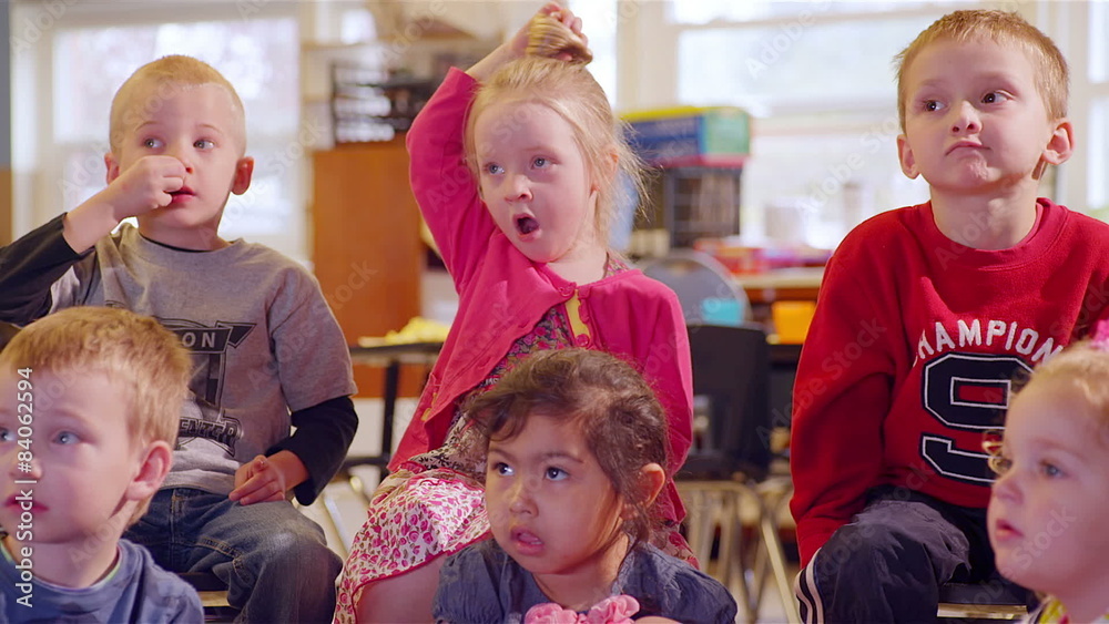 A large group of preschool students sit together and listen for show and tell A large group of preschool students sit together and listen for show and tell