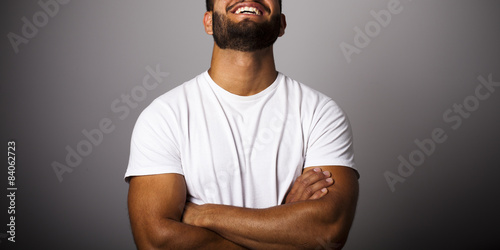 Hombre joven con barba y camiseta blanca con brazos cruzados photo