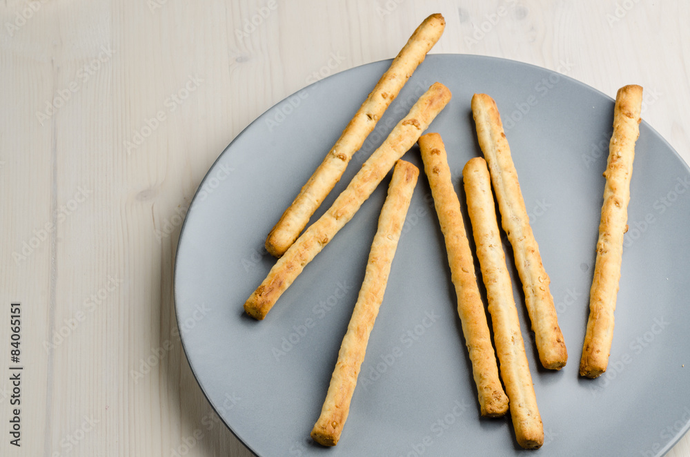 rustic breadsticks in a dish on wood table, close up, background