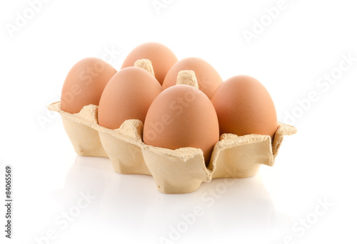 Foto Six brown eggs in carton on white with clipping path
