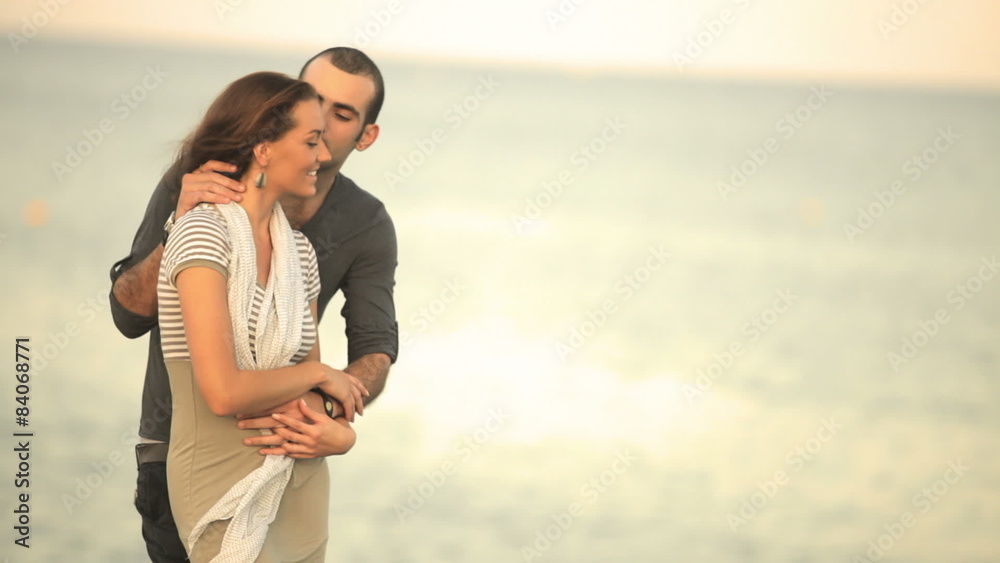 A young couple in love kiss on a cliff overlooking the ocean A young couple in love kiss on a cliff overlooking the ocean