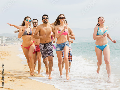 Positive friends running in swimwear