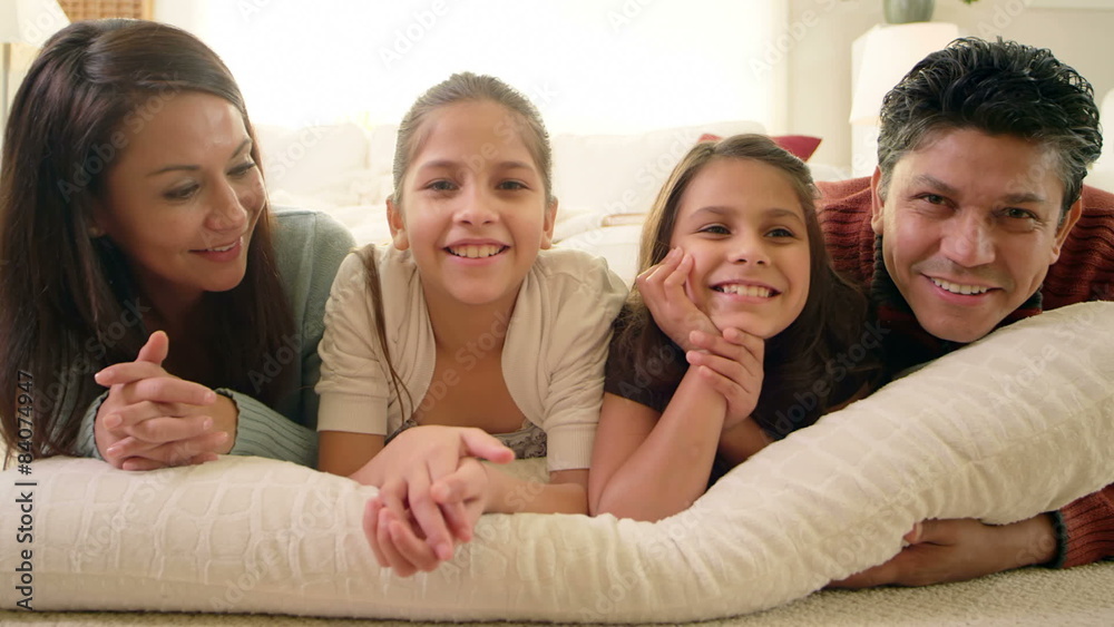 A cute family of four lie on a pillow together and all smile for the camera A cute family of four lie on a pillow together and all smile for the camera