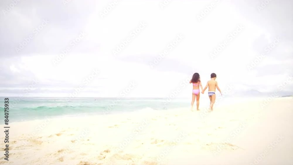 Siblings walk down a beach in Brazil Siblings walk down a beach in Brazil