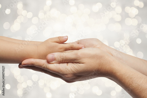 father and son holding hands on christmas lights background