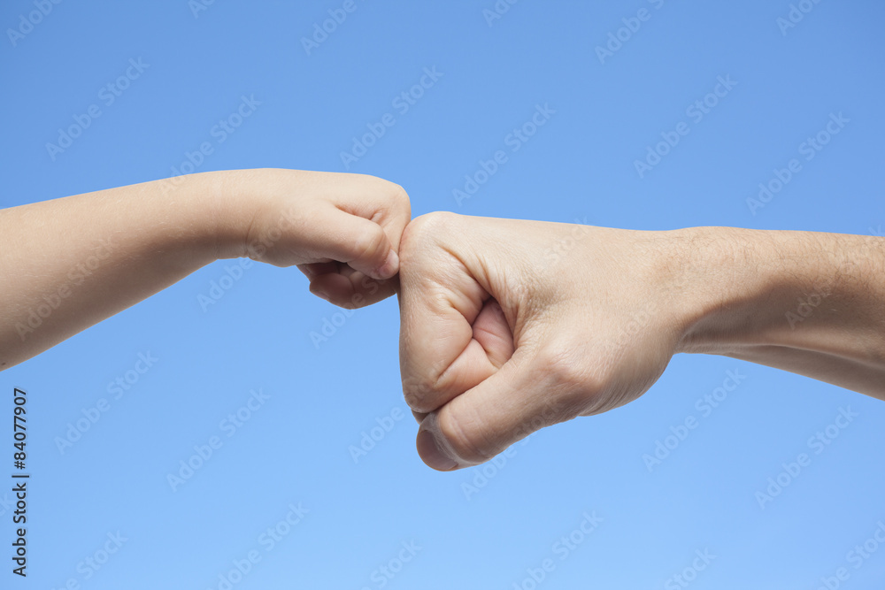 father and son punching fists for agreement on sky background