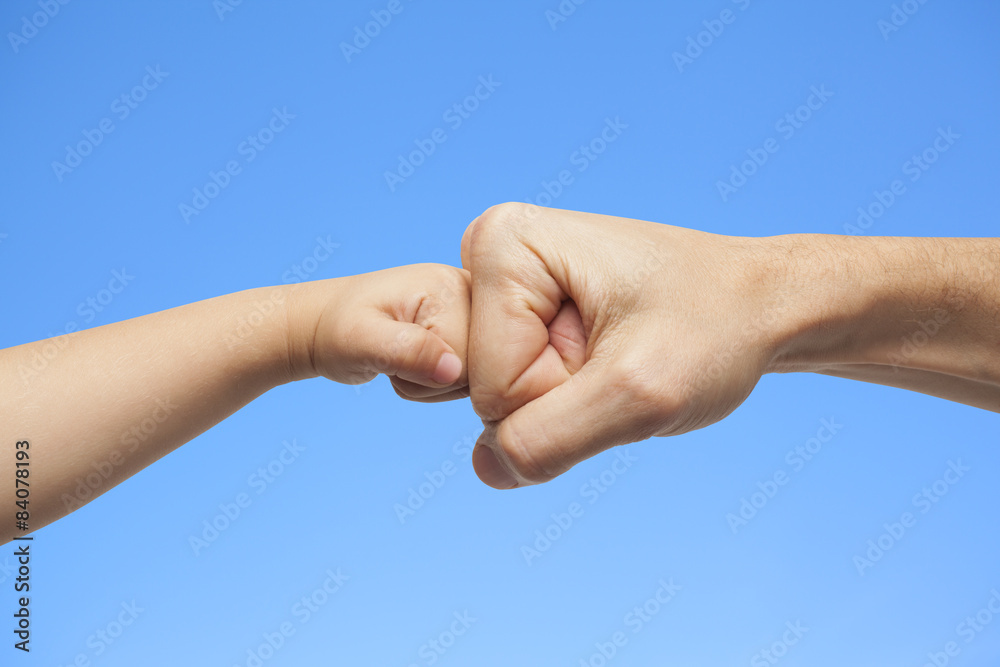 father and son punching fists for agreement on sky background