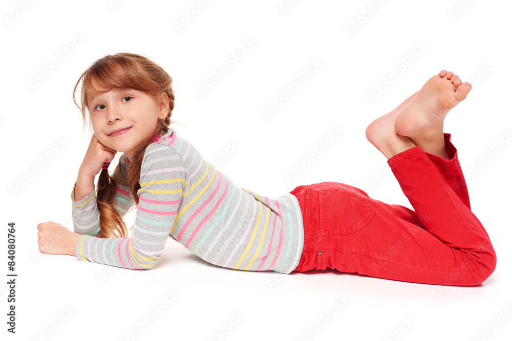 Foto de Side view of smiling child girl lying on stomach do Stock ...