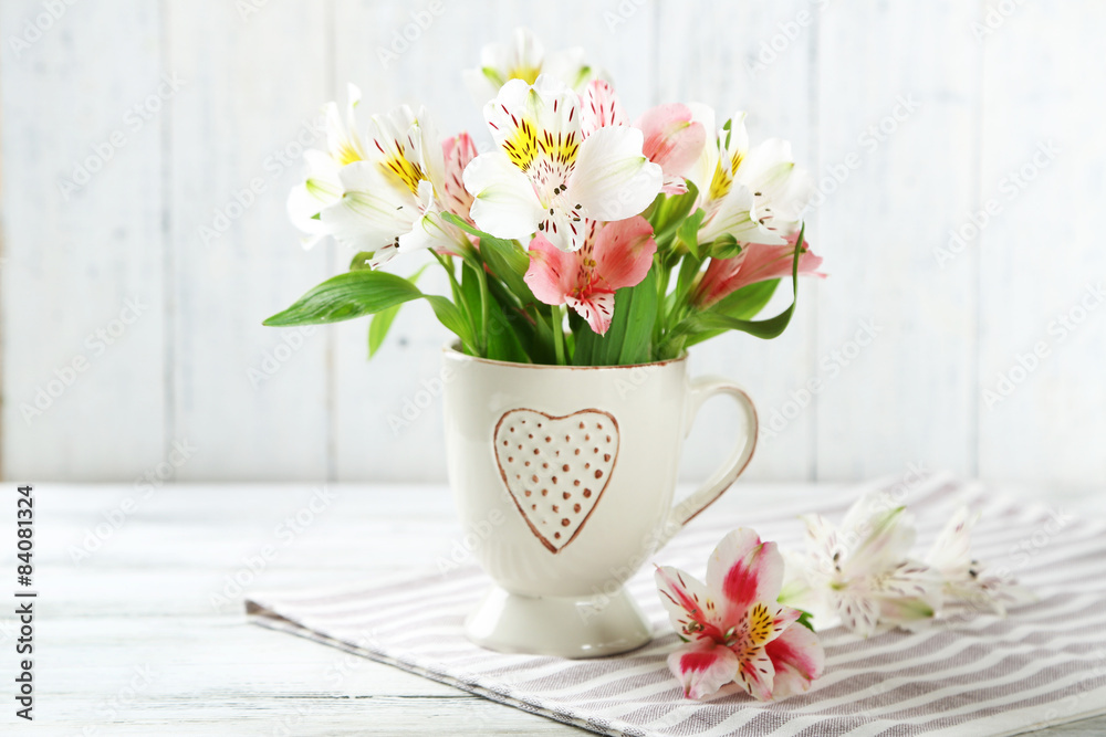 Obraz premium Beautiful flowers in cup, on wooden background
