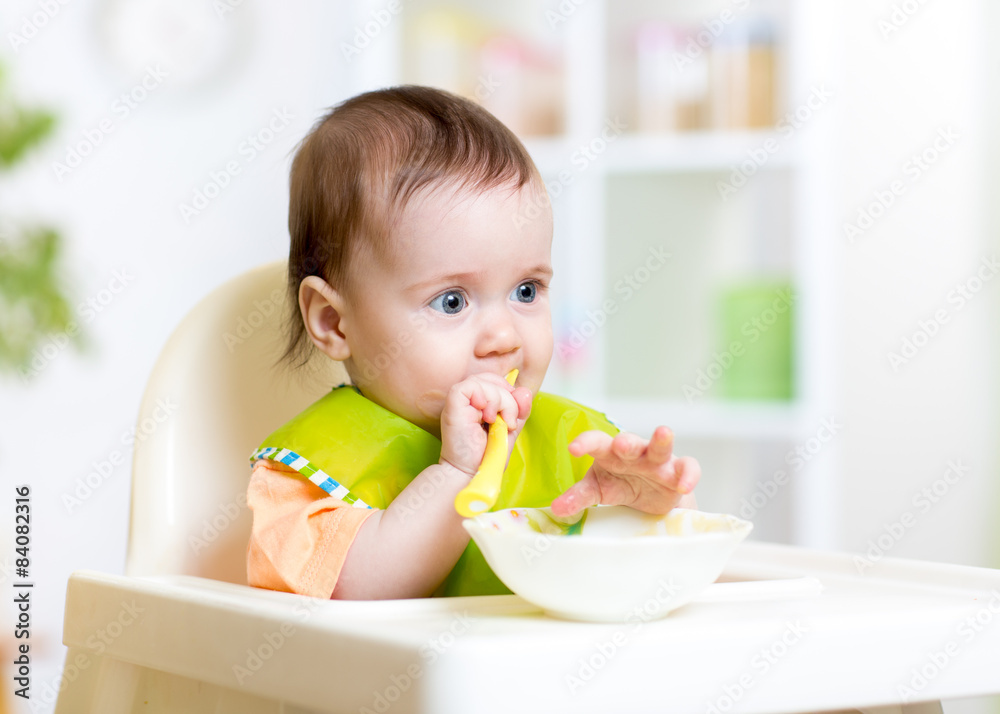 happy baby child sitting in chair with a spoon happy baby child sitting in chair with a spoon