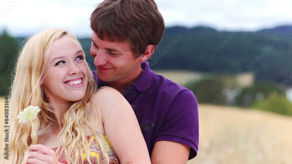 Boy walks up behind girl and wraps his arms around her. Boy walks up behind girl and wraps his arms around her.