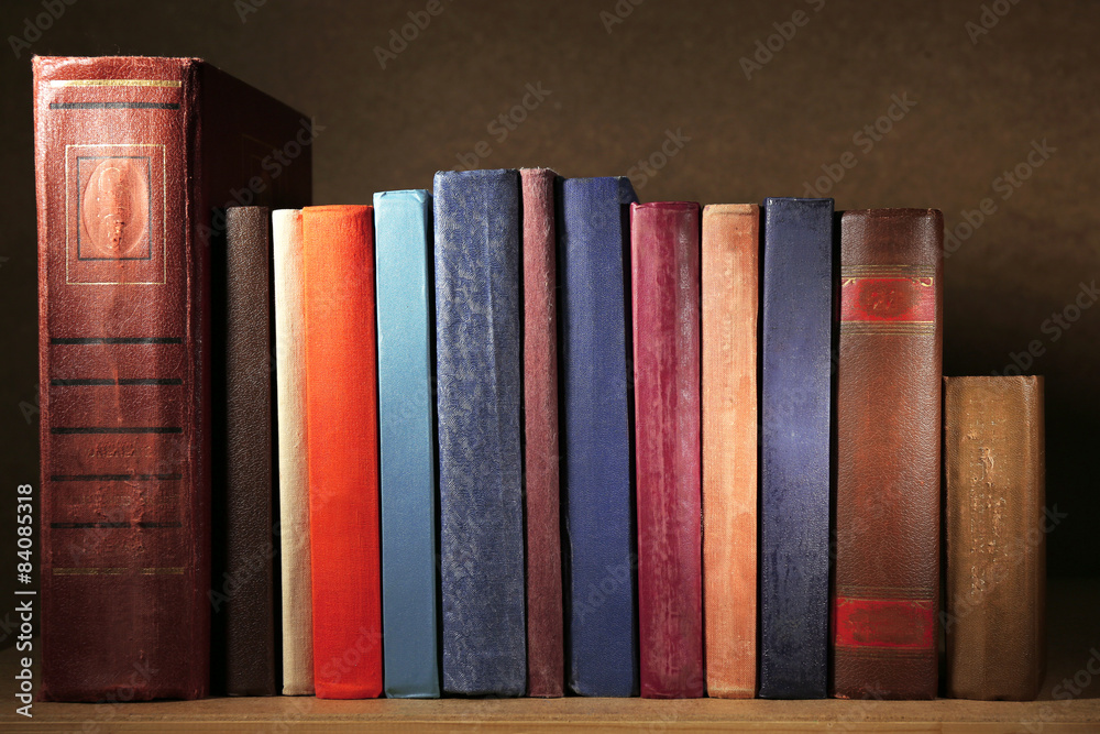 Naklejka premium Old books on shelf, close-up, on dark wooden background