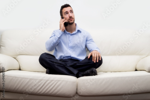 uomo di affari seduto su divano con smartphone che telefona