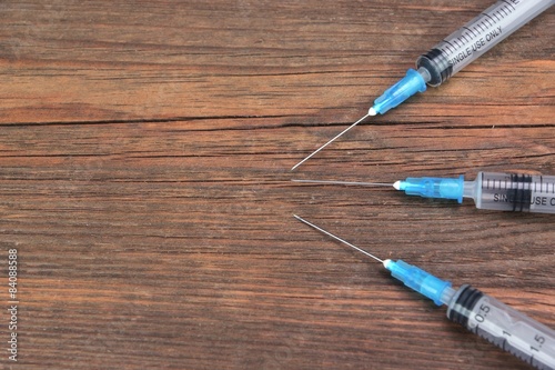 Three Empty Medical Syringes On Rough Wood Board
