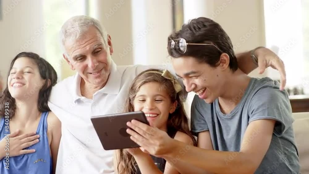 Grandfather using a tablet computer with grandchildren in living room Grandfather using a tablet computer with grandchildren in living room