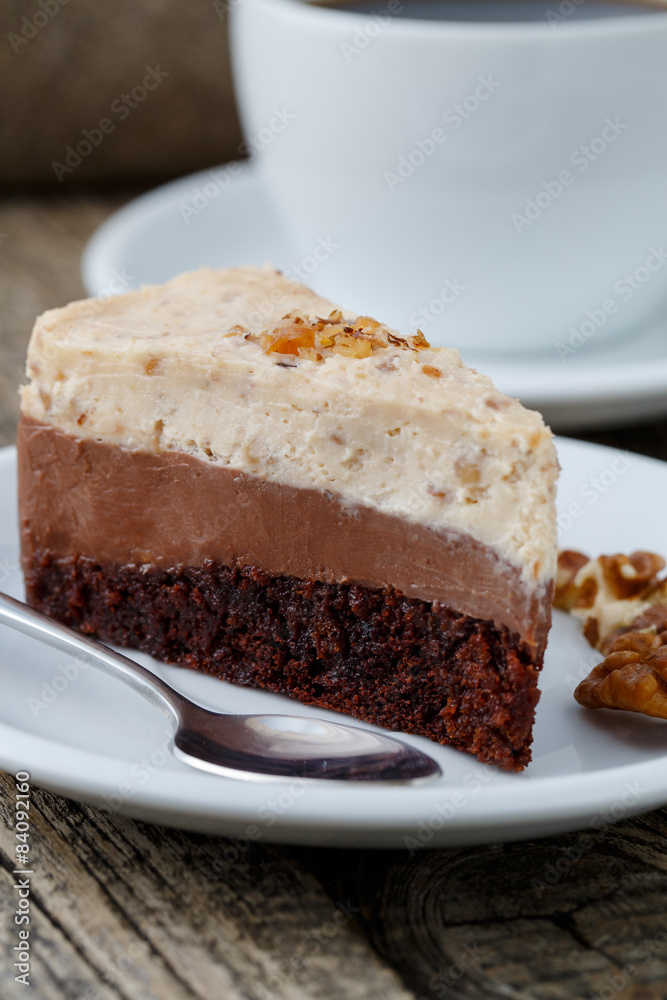 Tasty nuts cake with cup of coffee on wooden background.