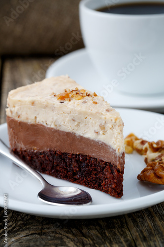 Tasty nuts cake with cup of coffee on wooden background.