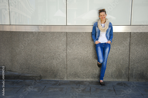 Beautiful urban woman, girl standing by the wall in city with je photo