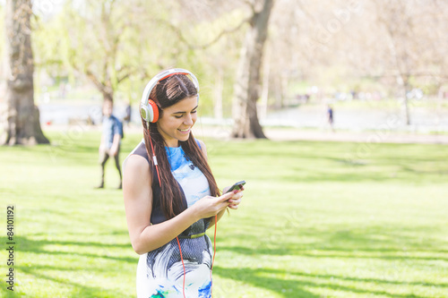 Young woman listening music at park in London © william87