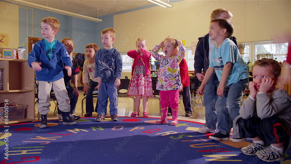 A group of young kids stand in a circle and do a dance together while in school