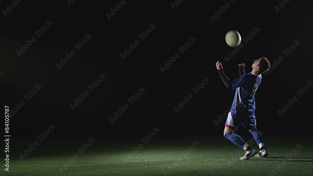 Soccer player in the shadows kicks a ball Soccer player in the shadows kicks a ball