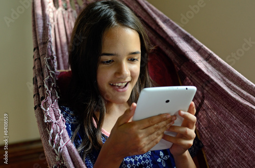 Little Hispanic girl using a tablet in a hammock
