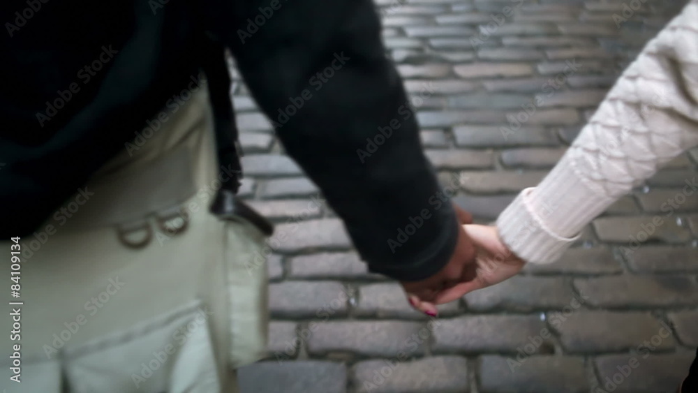 A cute couple walk down the street holding hands A cute couple walk down the street holding hands