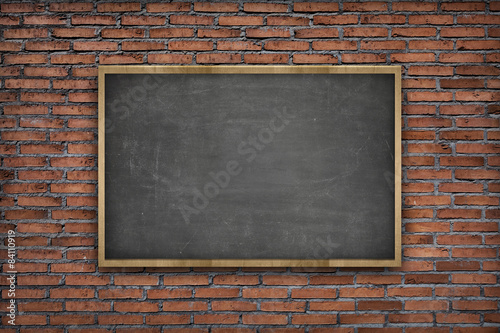 Black blank blackboard with wooden frame on brick wall