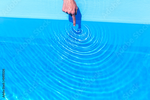 Forefinger making waves as circles in swimming pool