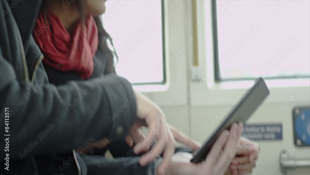 A couple laugh and smile together playing with their tablet on the bus A couple laugh and smile together playing with their tablet on the bus