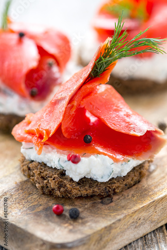 Sandwich of black bread  cheese with herbs and red salmon.