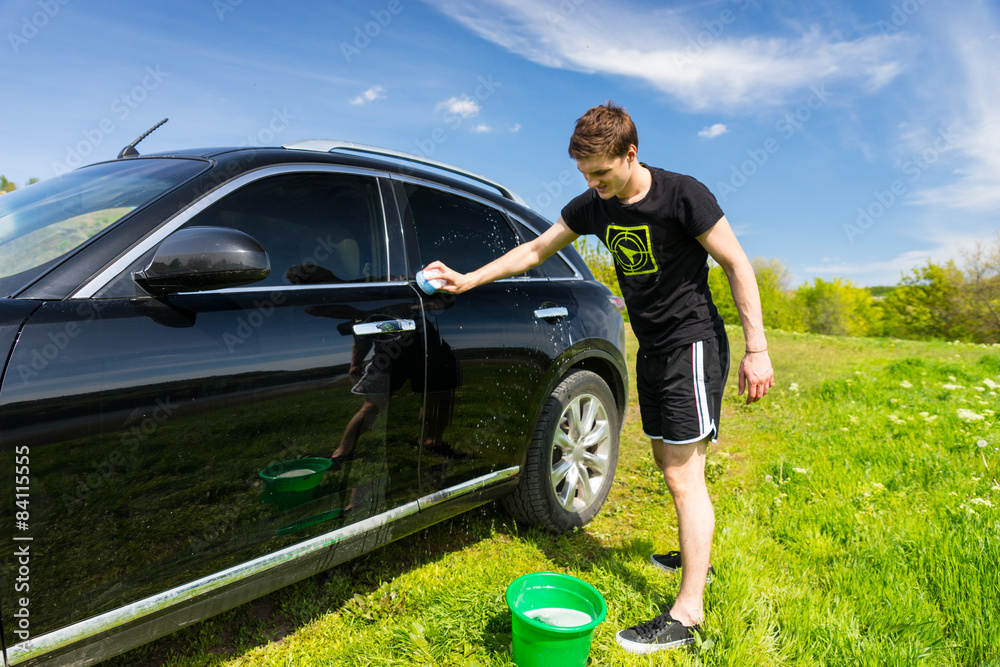 Man Washing Car in Field on Sunny Day Man Washing Car in Field on Sunny Day