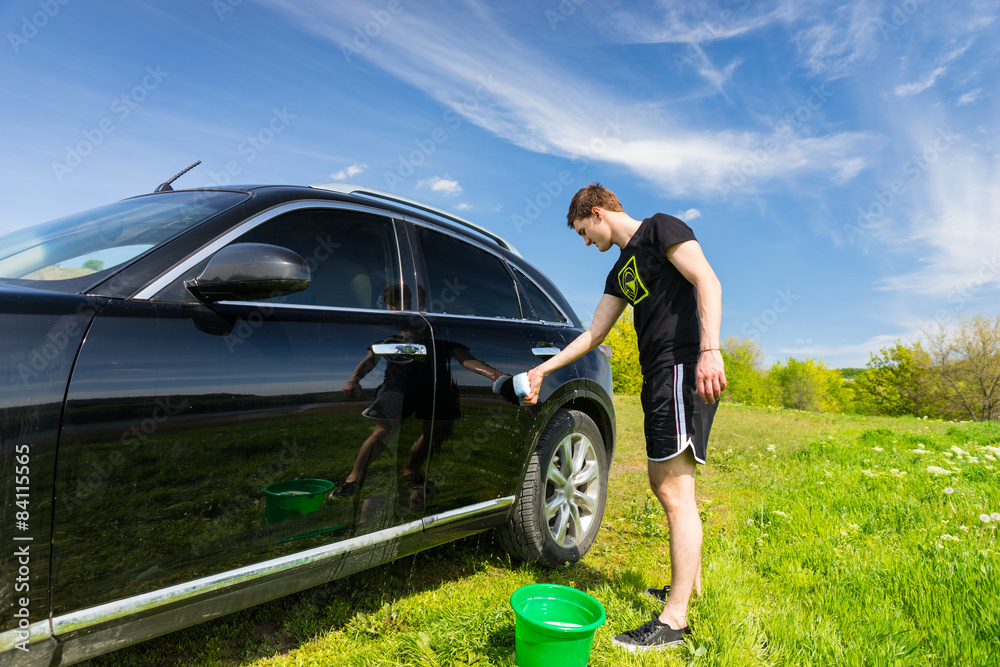 Man Washing Car in Field on Sunny Day Man Washing Car in Field on Sunny Day