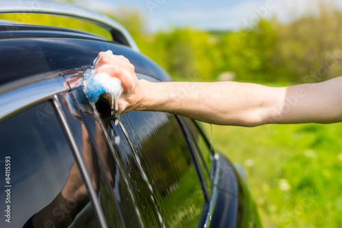 Man Washing Black Car with Soapy Sponge