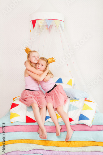Two little girl lying on a pile of mattresses.